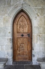 Wooden door with carvings and religious symbols in stone arch, Gothic architecture in the cloister