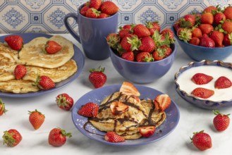 Pancakes with strawberries Chocolate syrup next to fresh strawberries and yoghurt in blue crockery
