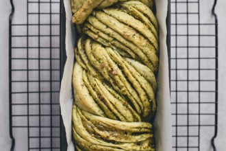 Baked homemade savoury babka plaited bread loaf flavoured with cheese and pesto, in the making tin