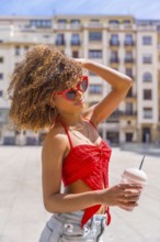 Vertical side view portrait of a sensual woman in summer clothes drinking shake in the city