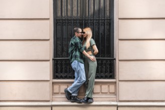 A Colombian lesbian couple stands lovingly in an urban setting, symbolizing pride and identity.