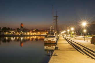 Sailing boats in the port of Wolgast at dusk, blue hour, in the back the old town with St. Peter's