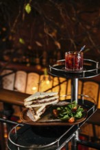 A delectable club sandwich with veal cheeks and cheese, paired with a refreshing Negroni cocktail.