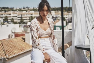 A stylish woman enjoys a sunny day on a rooftop, wearing trendy summer fashion The urban backdrop