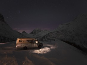 Winter motorhome under a starry sky on the island of Senja in a serpentine, Troms, Norway