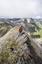 Mountaineer on a steep rocky ridge, on the summit of the Lasörling, Lasörling Group, Hohe Tauern