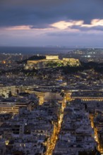View over the sea of houses of Athens, illuminated Parthenon temple on the Acropolis, dramatic