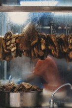 Unrecognizable person preparing traditional street food in Hong Kong, with hanging dried items and