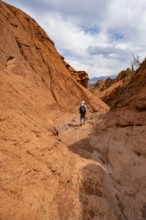 Mountaineers in a canyon with a dry stream bed, eroded mountain landscape with red sandstone rocks,
