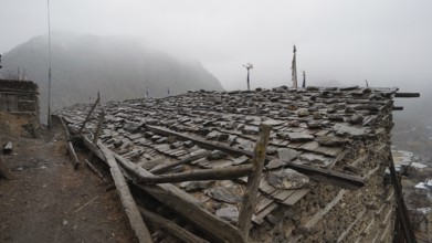 Stone roof of an old building in a foggy mountain village, trekking at Annapurna Circuit, Manang,