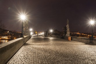 Illuminated at night, Charles Bridge in Prague showcases statues and cobblestones under glowing