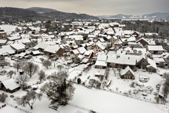 Snowy village with characteristic half-timbered houses under grey skies, Herleshausen in northern