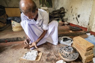 A man is busy with coal and a newspaper clipping in a quiet workshop, a man is burning sapphires in