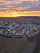 Overview of a town in twilight with a sky in golden tones and cloud formations, aerial view, Calw