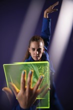 A young woman engages with a neon green futuristic device, highlighting modern technological