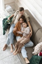 Top view image of a family of four celebrates Christmas in a warm, cozy setting. The mother,