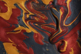 Vibrant swirls of metallic red, gold, and black paints merge, forming a captivating abstract