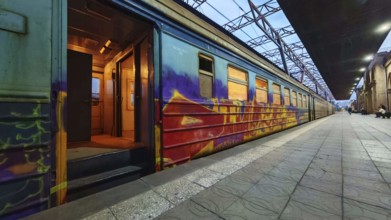 A graffiti-decorated train on the platform at dusk, Yerevan, Armenia