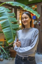 Vertical portrait of a beauty young female entrepreneur standing outside a coworking office holding