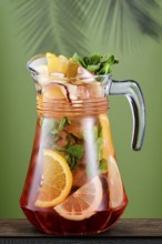 Pitcher with cold citrus sangria over green background