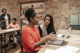 A diverse group of professionals engages in discussion within a modern coworking space,