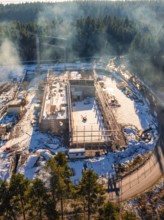 Snow-covered construction site with scaffolding and crane in the wintry forest, new fire station,