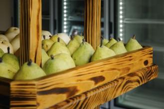 Fresh green pears neatly arranged in a rustic wooden display case at a market in Tulum, Mexico. The