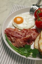 Breakfast, fried egg, bacon and bread, with cherry, on a light background, homemade, no people