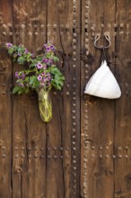 Rustic wooden door with a bouquet of flowers and antique door hook, Pollensa, Majorca, Balearic