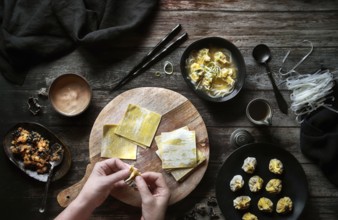 Top view of anonymous woman preparing wonton soup on a wooden table