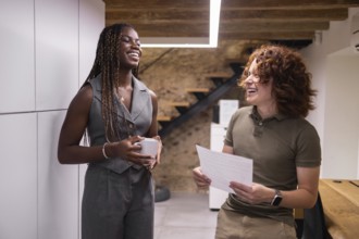 Two coworkers enjoy a lighthearted conversation in a modern office setting, fostering a positive