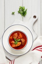 Potatoes stewed with meat, in tomato sauce, with spices and herbs, no people, on a white table