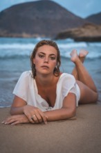 Lifestyle of a blonde Caucasian girl in a white swimsuit. Lying on the sand after getting out of