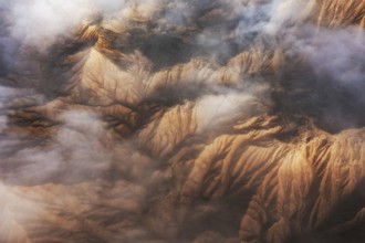 Captivating aerial view showcasing majestic mountain peaks partially enveloped in soft, swirling