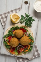 Tortillas, wrapped falafel balls, with fresh vegetables, vegetarian healthy food, on a wooden white