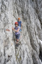 Two mountaineers with helmets climbing on a rock face, ascent to the Ackerlspitze, Wilder Kaiser,