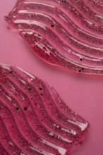 A detailed view of pink scrub and cosmetic gel, elegantly smeared on a pink surface, showcasing the