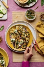 Top view of cropped unrecognizable hand serving a beautifully garnished roasted courgettes served