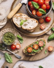 Rustic toasts topped with vibrant cherry tomatoes and fragrant pesto, presented on a wooden board.