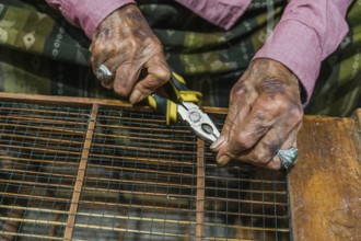 Close up of balinese hands using pliers to craft with wire. The image captures the essence of