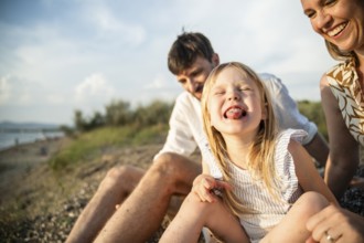 A joyful family enjoys a sunny day on a picturesque Italian beach. The playful child is the center