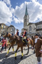 Historically costumed guild members in Zurich's old town, riders in front of the Fraumünster