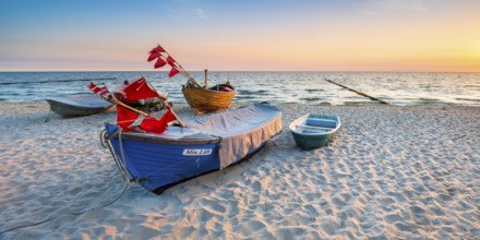 Fishing boats with red flags on fine sandy beach at sunrise, Baltic resort Kölpinsee, Usedom