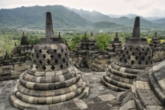 Majestic view of the Borobudur Temple's ancient stone stupas, with vibrant green mountains and lush