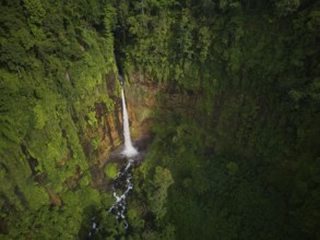 Aerial shot capturing the majestic Kaspa Biru Waterfall descending into a natural gorge, surrounded