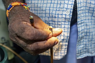Close-up of a hand with a colored bracelet holding a small object, the gemstone cutters in the city