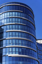 A stunning example of modern architecture featuring a curved glass facade with visible concrete and