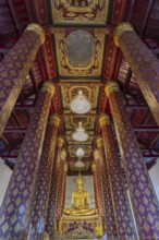 Golden Buddha statue, Phra Phuttha Nimit, and coffered ceiling in the ubosot of Wat Na Phra Men,