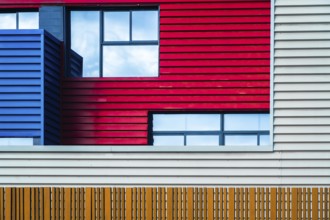 This image captures the vibrant and modern urban facade of a building, featuring a bold mix of red,