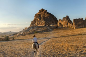 A local Turkish man rides a horse through the volcanic landscape of Cappadocia, known as the land